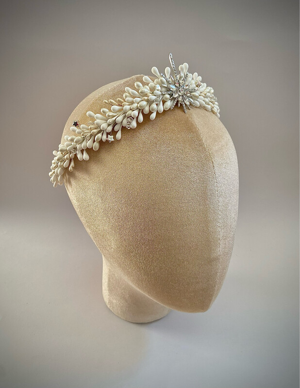 Tiara de novia compuesta por un sinfín de pistilos blancos y nacarados de unos 34 cm de longitud aproximadamente terminada con una estrella central en base dorada o plateada.

Queda preciosa si la combinas con horquillas en la parte trasera de la cabeza ya que se conseguimos equilibrar el look aportando luminosidad en la zona posterior.

Su peculiaridad es que puede utilizarse también como tocado trasero por su tamaño, consiguiendo con una misma pieza lucir dos looks.

No dudes en preguntar por personalizaciones para esta pieza incluyendo pistilos de otras tonalidades.
