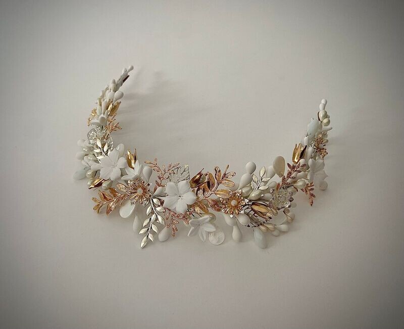 Diadema de novia Elevada Etérea Diadema elevada compuesta por muchos pequeños detalles dentro de los que destacan las flores, las ramas, las hojas y los pistilos.
Su característica principal es la alternancia de los detalles, consiguiendo un efecto fresco y desenfadado.
Su peculiaridad es que puede utilizarse también como tocado trasero O diadema sin altura consiguiendo con una misma pieza lucir dos looks.