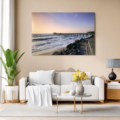 Canvas print of coastal pier at sunset hanging in modern living room interior