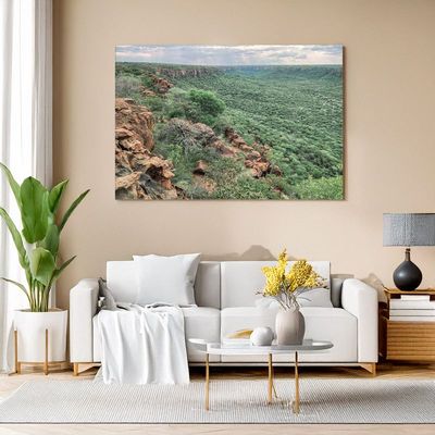 Modern living room with white sofa, canvas of a vast green valley and red rock cliffs under a soft sky.