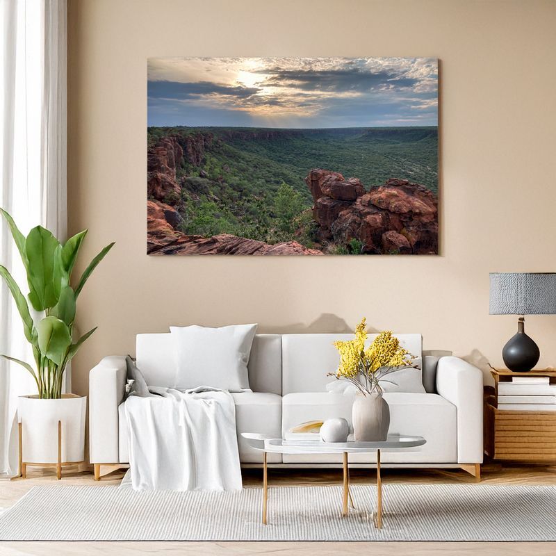 Modern living room with white sofa, canvas of a red rock canyon with sunlit sky over a green valley.