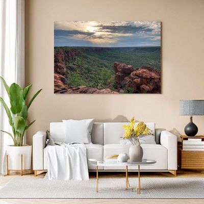 Modern living room with white sofa, canvas of a red rock canyon with sunlit sky over a green valley.