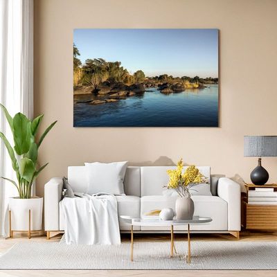 Modern living room with wall art of a tranquil river landscape at sunset.