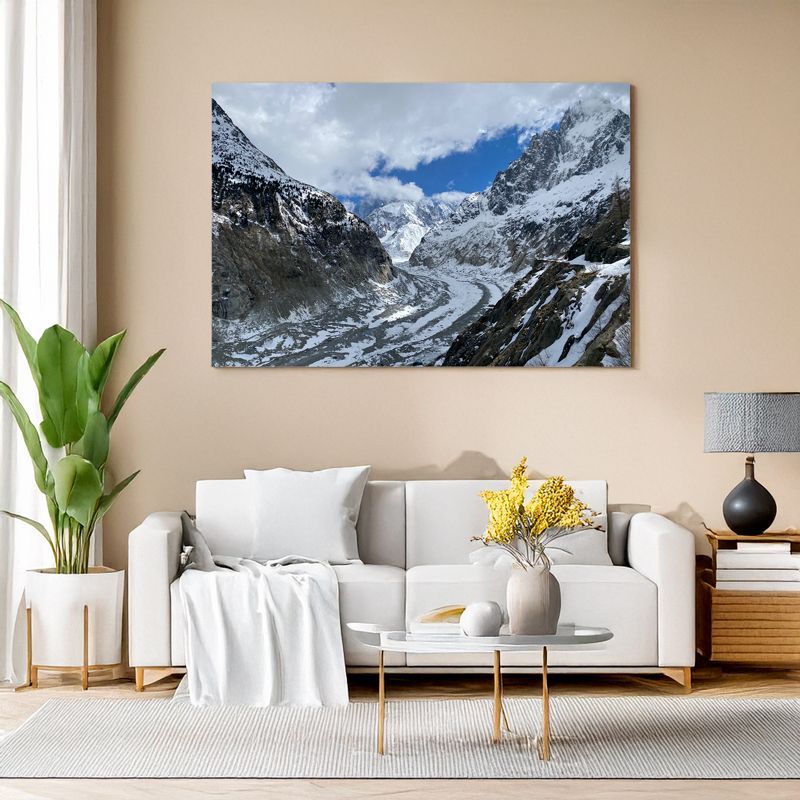 Wohnzimmer mit Leinwandbild einer Gletscherlandschaft zwischen hohen Bergen.