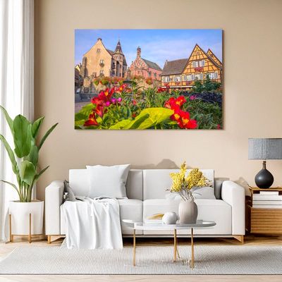 Leinwand mit blühenden Blumen und Fachwerkhäusern im Hintergrund.