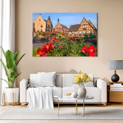Leinwand im Wohnzimmer zeigt Dorfplatz mit Fachwerkhäusern und Blumen.