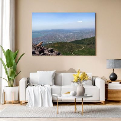 Leinwand über Sofa zeigt Panorama mit Vulkanlandschaft und weitem Blick ins Tal.