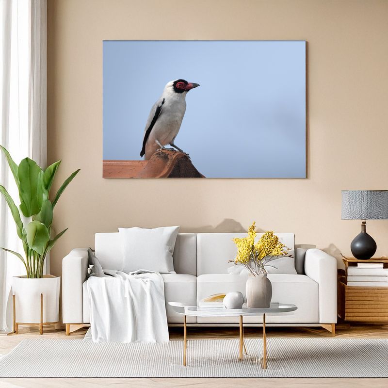 Wall art of a red-faced bird on a roof shown above a bright white sofa.