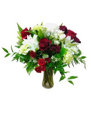 Primrose bouquet with white lilies and red roses in a clear vase