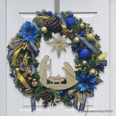 Nativity Christmas wreath hanging on a front door with red poinsettias and manger scene
