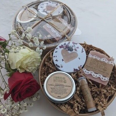 Spa gift basket with bath products and red rose beside open lid
