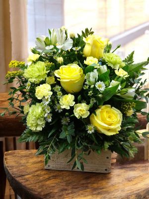 Yellow roses rustic flower arrangement in wooden box with solidago, alstroemeria, mini carnations and greenery
