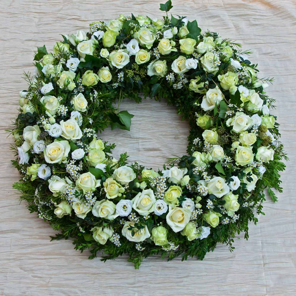 Couronne funéraire de fleurs blanches et vertes posée sur une table
