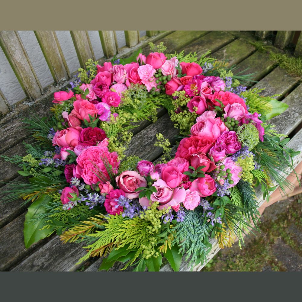 Couronne funéraire de fleurs roses sur un banc en bois