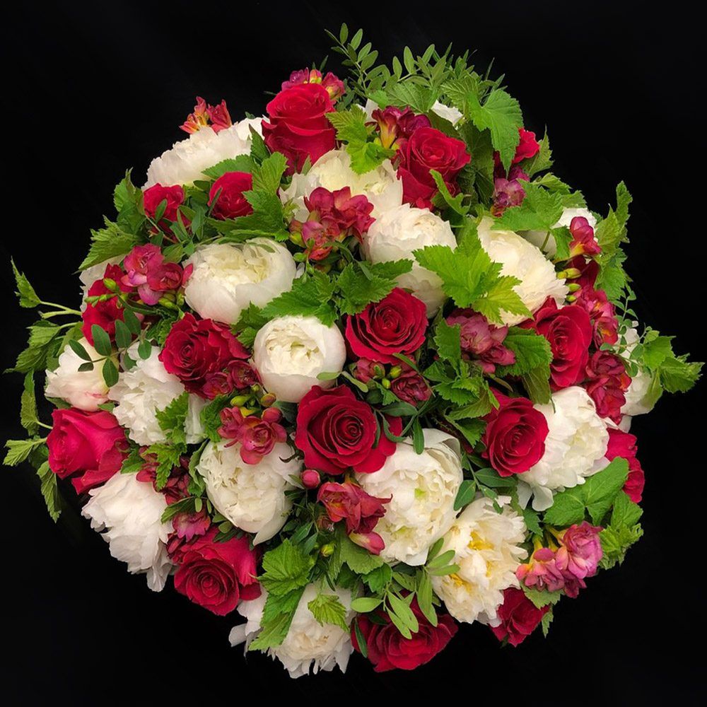 Bouquet rond de roses rouges et pivoines blanches sur fond noir