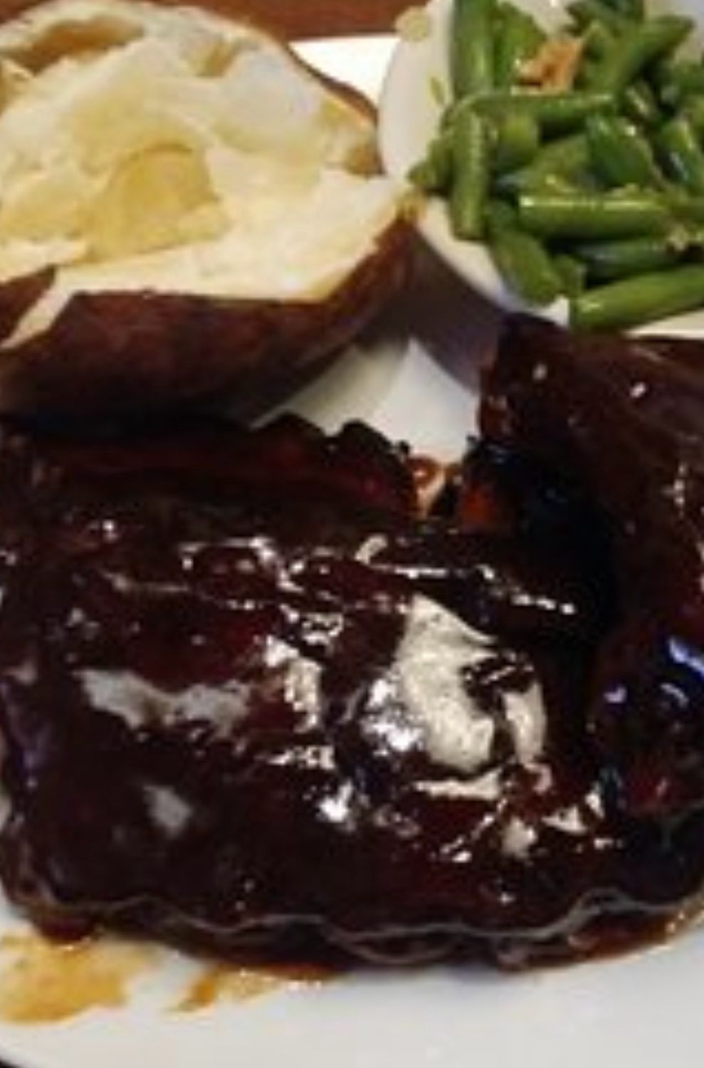 Tender Baby Back Ribs Slow-cooked to perfection, served with a foil-baked potato and fresh snipped green beans.