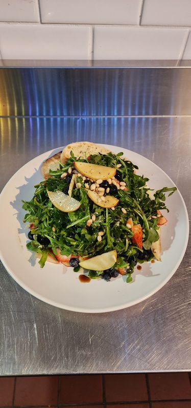 Rocket Salad Salad Plate with Arugula, Apples, pine nuts and bread on a stainless steel counter top