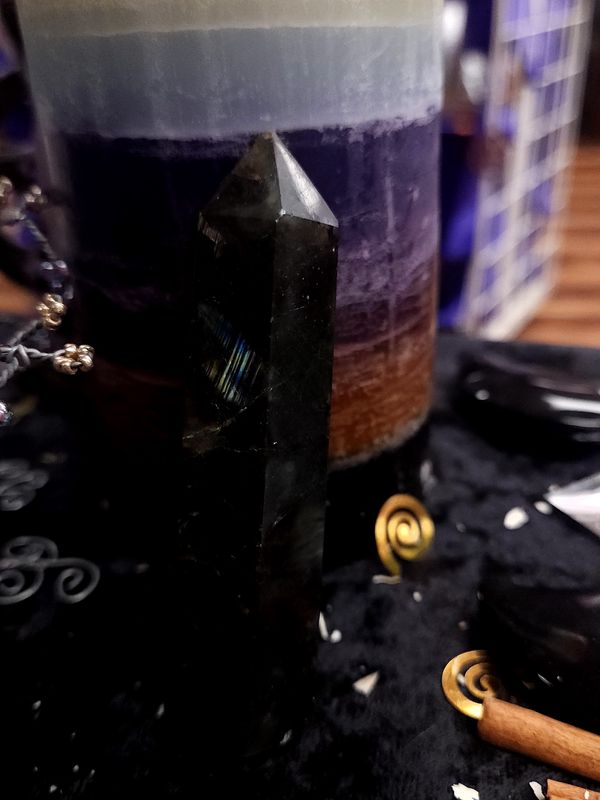Aurora Flash Labradorite Tower 90mm Dark 90mm labradorite tower showing a bright blue-gold flash on one face, standing on a black altar cloth