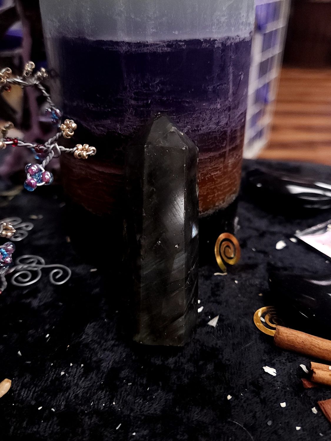 Midnight Mist Labradorite Tower 70mm Dark 70mm labradorite tower with soft gray-green bands, standing on a black altar cloth before a layered purple candle.