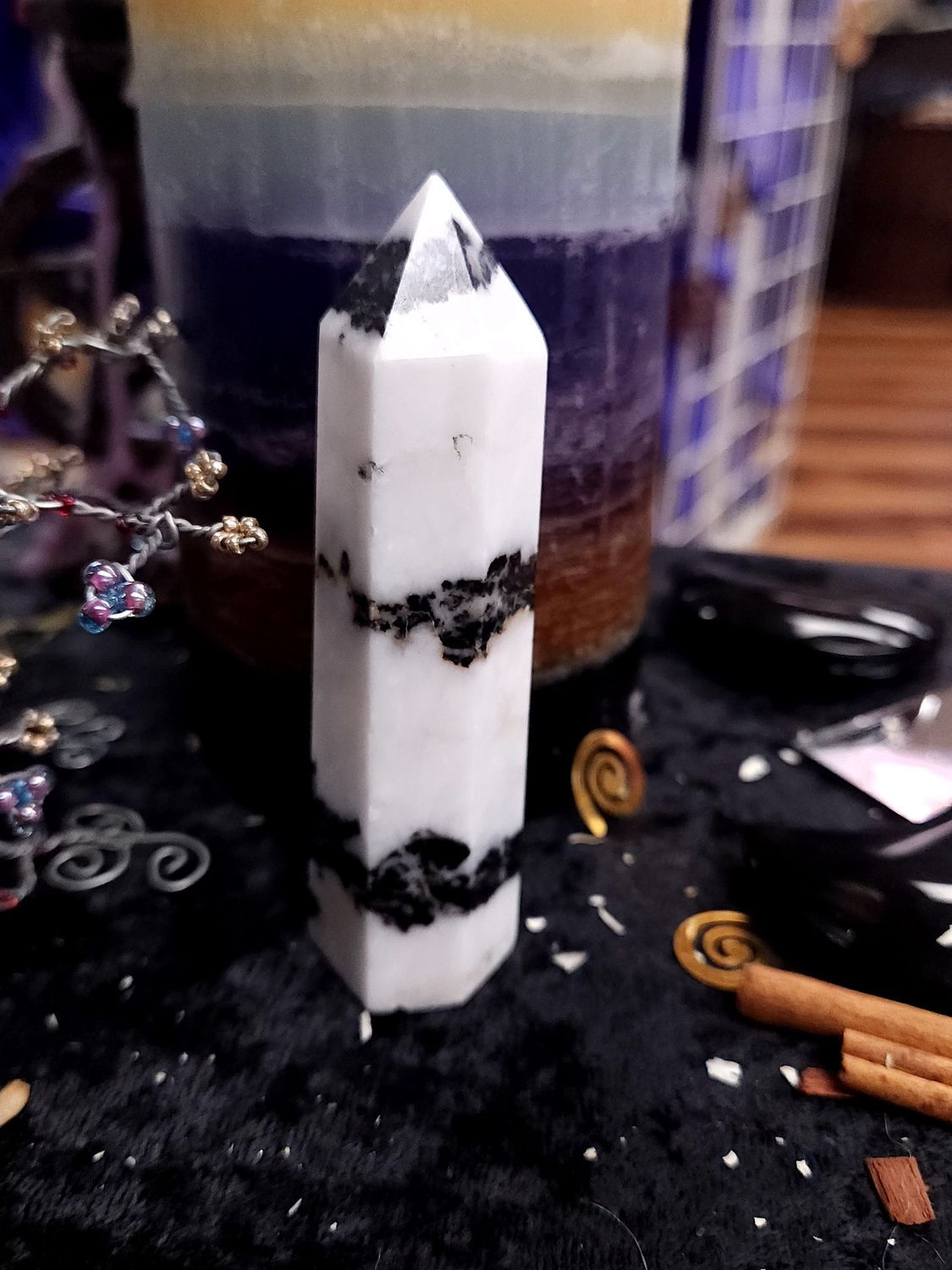 Tall 96mm zebra jasper tower with strong black bands around white stone on a black altar cloth before a layered purple candle
