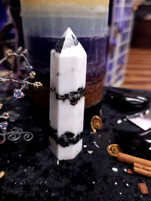 Midnight Stripe Zebra Jasper Tower 96mm Tall 96mm zebra jasper tower with strong black bands around white stone on a black altar cloth before a layered purple candle