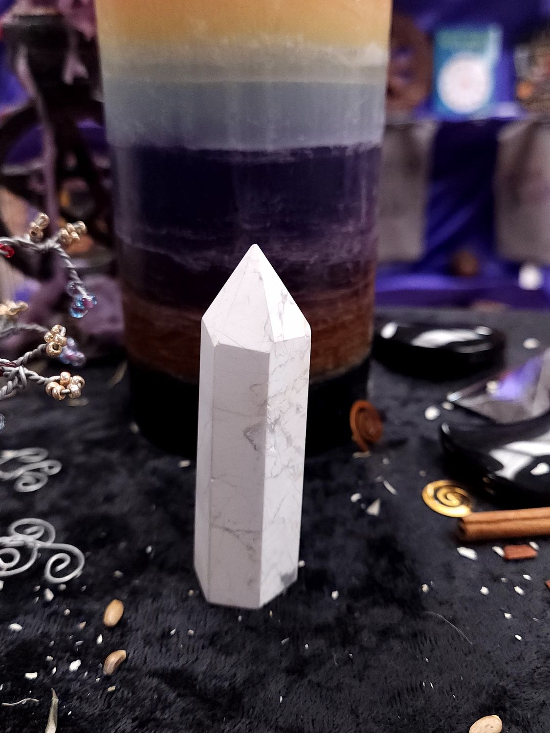 Soft Focus Howlite Tower 77mm Short 77mm white howlite tower with light gray veining on a black altar cloth before a rainbow pillar candle.