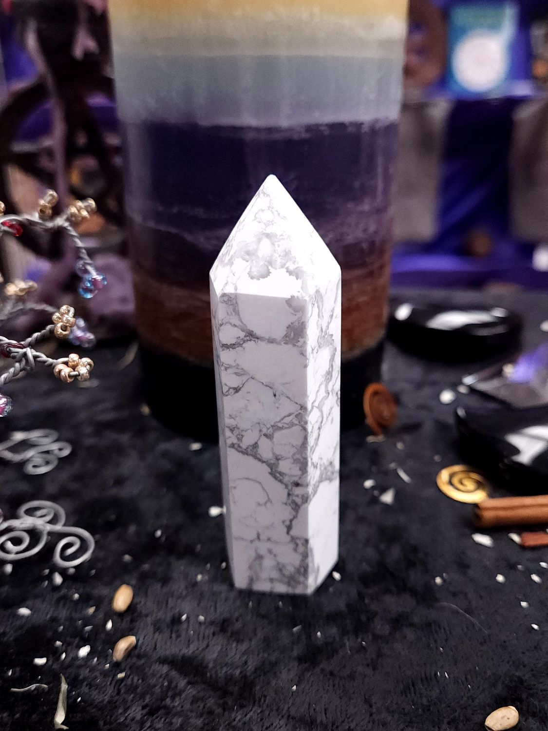 85mm white howlite tower with gray web-like veining on a black altar cloth before a rainbow pillar candle.