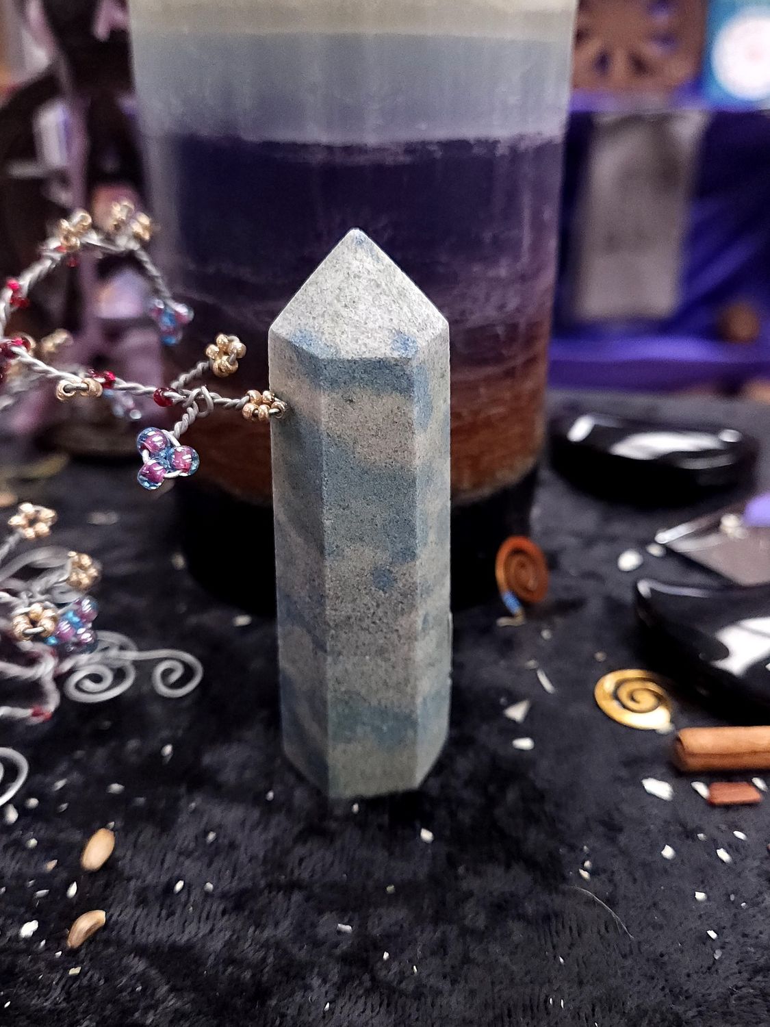 High Peak K2 Stone Tower 82mm 82mm K2 stone tower with gray granite and soft blue spots on a black altar cloth before a rainbow pillar candle.