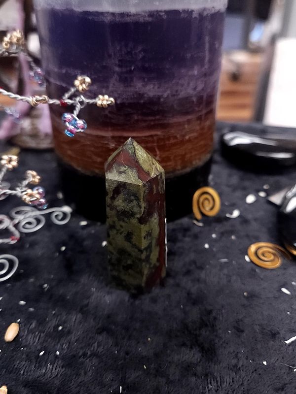 Dragon's Blood Jasper Tower 55mm Small dragon’s blood jasper tower with green and red patterns on a black altar cloth in front of a purple layered candle