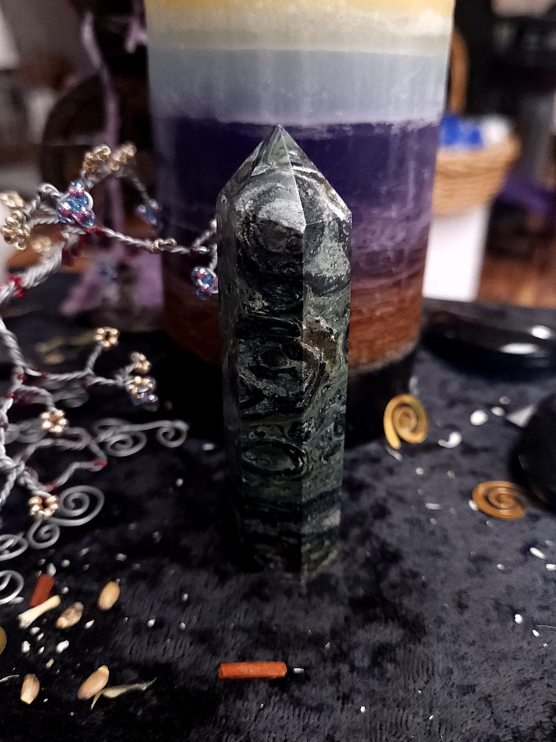 Kambaba Jasper Crystal Tower 92mm Tall kambaba jasper crystal tower with dark green and black circular patterns on a black altar cloth in front of a candle