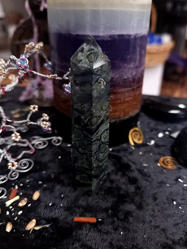 Kambaba Jasper Crystal Tower 93mm Tall kambaba jasper crystal tower with dark green circular patterns on a black altar cloth in front of a purple candle