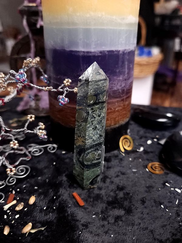 Kambaba Jasper Crystal Tower 84mm Medium kambaba jasper crystal tower with green circular “fingerprint” patterns on a black altar cloth in front of a candle