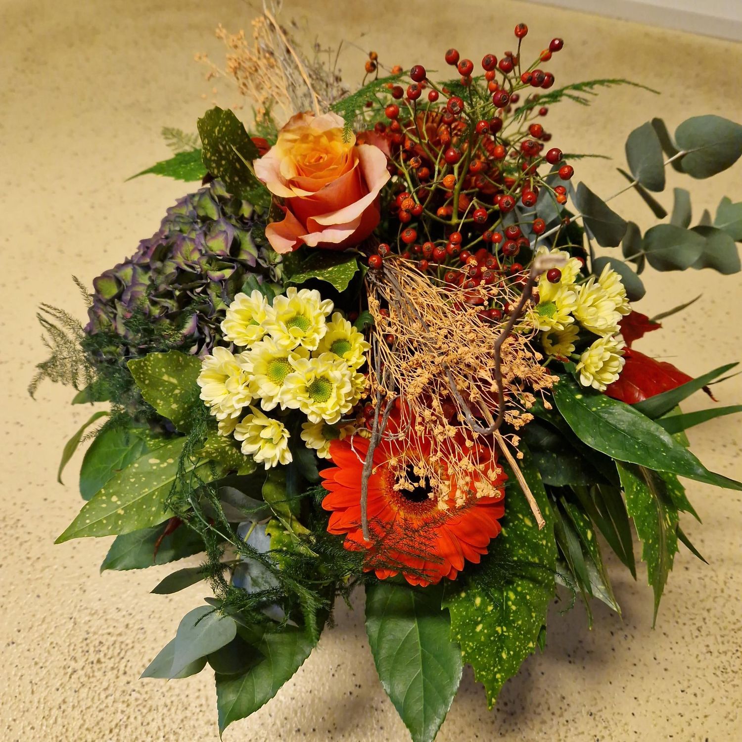 Fröhlicher Herbststrauss mit Halmen und Blättern, orange/rot/gelb