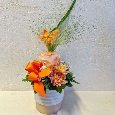 Gestuftes kleines Gesteck, orange/lachs/ mit Schleife und Deko-Schmetterling