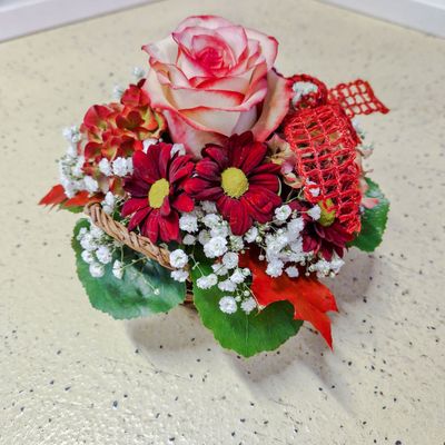 Kleines Gesteck mit Rose und Band in Korb, rot/weiss Kleines Gesteck mit Rose und Band in Korb, rot/weiss