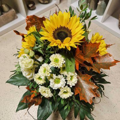 Locker gebundener Strauss mit drei Sonnenblumen, gemischten Blumen und Herbstblättern