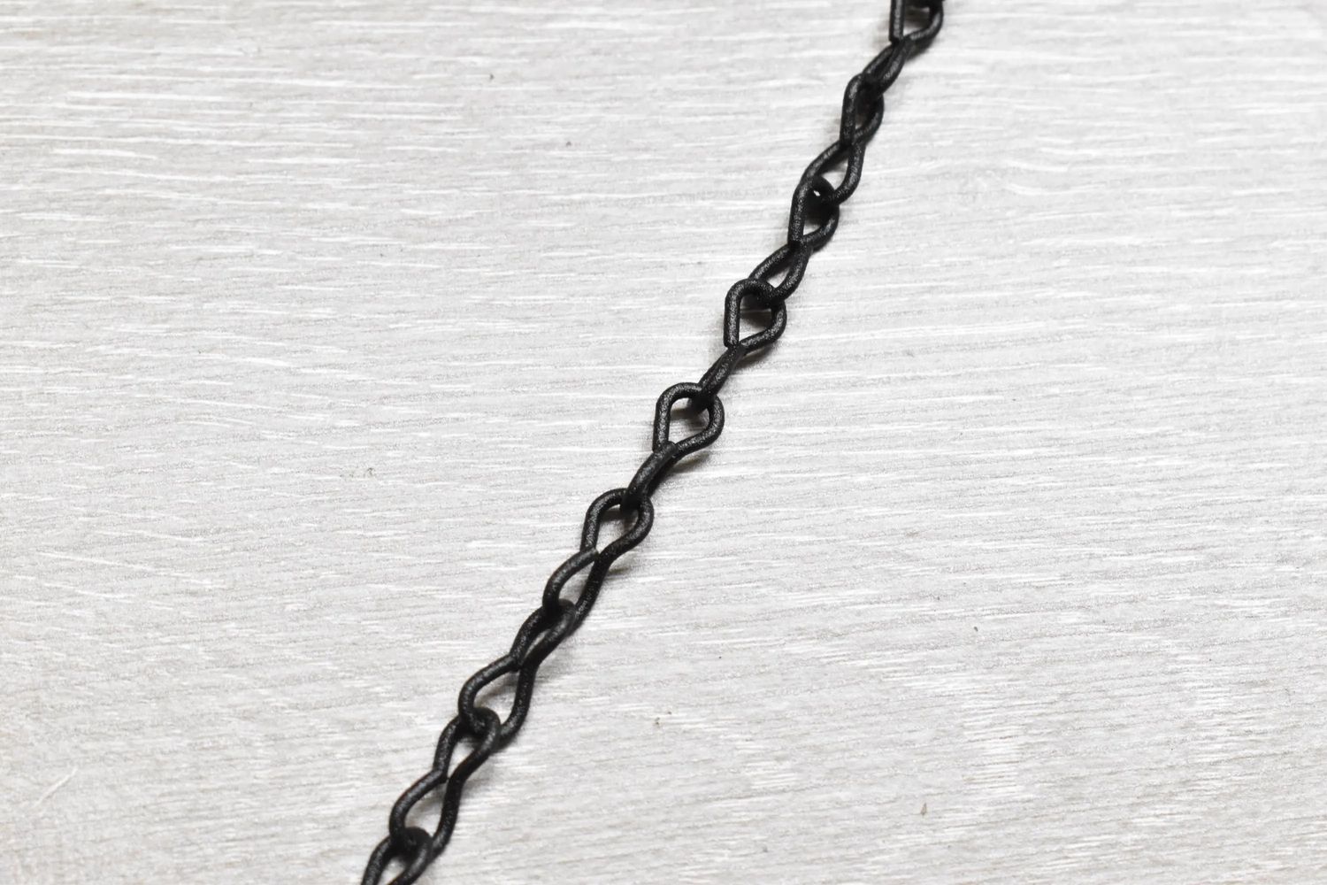 10 ft decorative #16 black powder coated chain shown coiled on surface, rated for 10 lb max load, ideal for indoor or outdoor