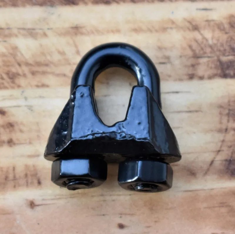 1/8 inch powder coated wire rope clip with U-bolt and saddle, shown assembled on wood surface for product display.