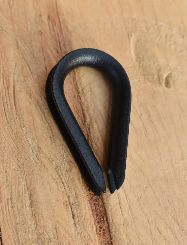 Close-up of 1/8 inch wire rope thimble with custom powder coated finish, placed on natural wood surface.