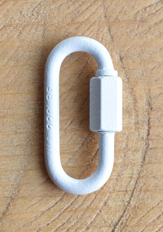 Close-up of a 1/8 inch quick link metal connector with threaded screw lock, shown on a wooden surface.