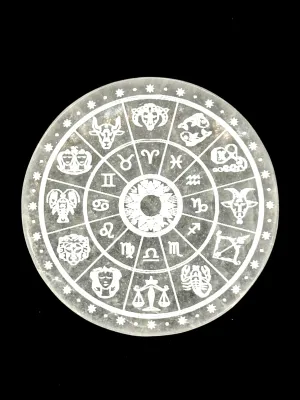 Round white selenite plate engraved with a wheel of the twelve zodiac signs, on a black background.