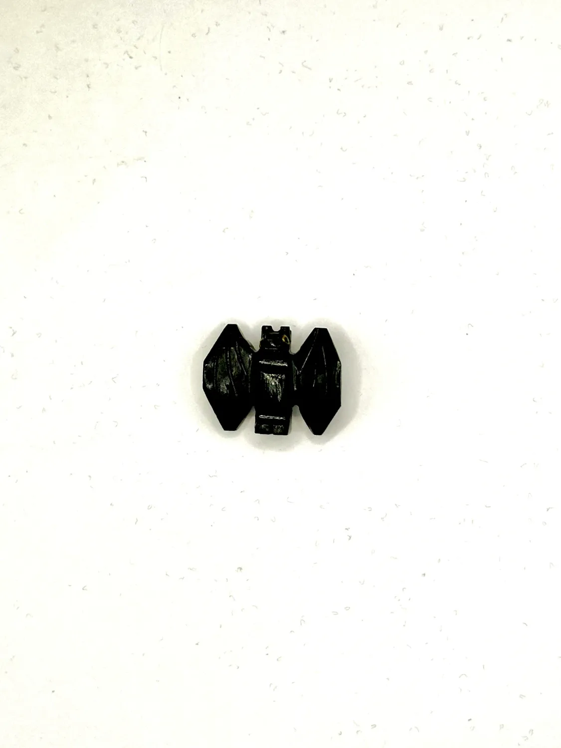 Black onyx bat carving with faceted wings spread, on a white surface.