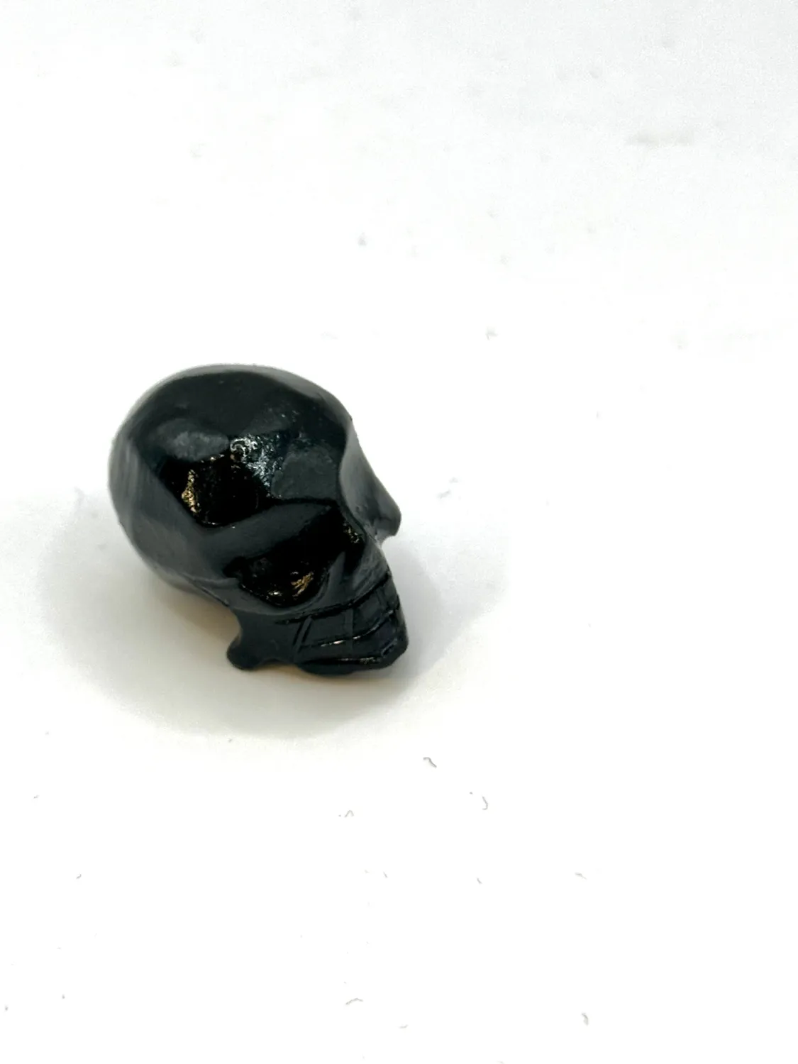 Glossy black onyx skull carving seen from above at an angle, on a white surface.