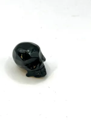 Glossy black onyx skull carving seen from above at an angle, on a white surface.