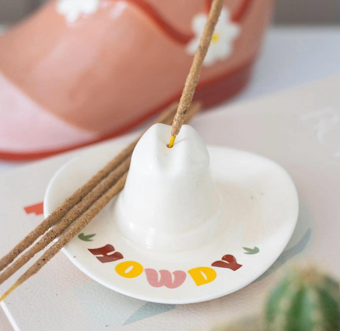This cute incense stick holder is perfect for unwinding after a long day on the trail. Shaped like a mini cowboy hat with a retro &#39;Howdy&#39; message along the brim, it adds a playful Western vibe and can