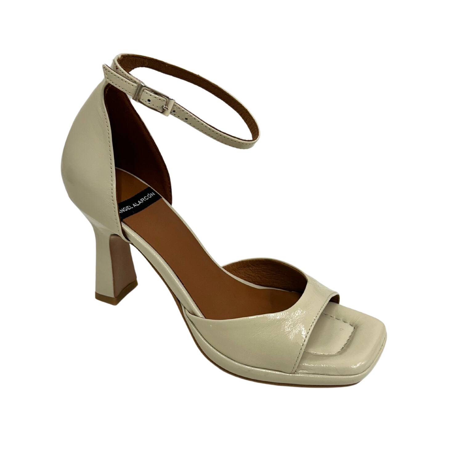Angled front shot of a creamy white dress shoe.  Open to closed heel.  Ankle strap with buckle adjustment
