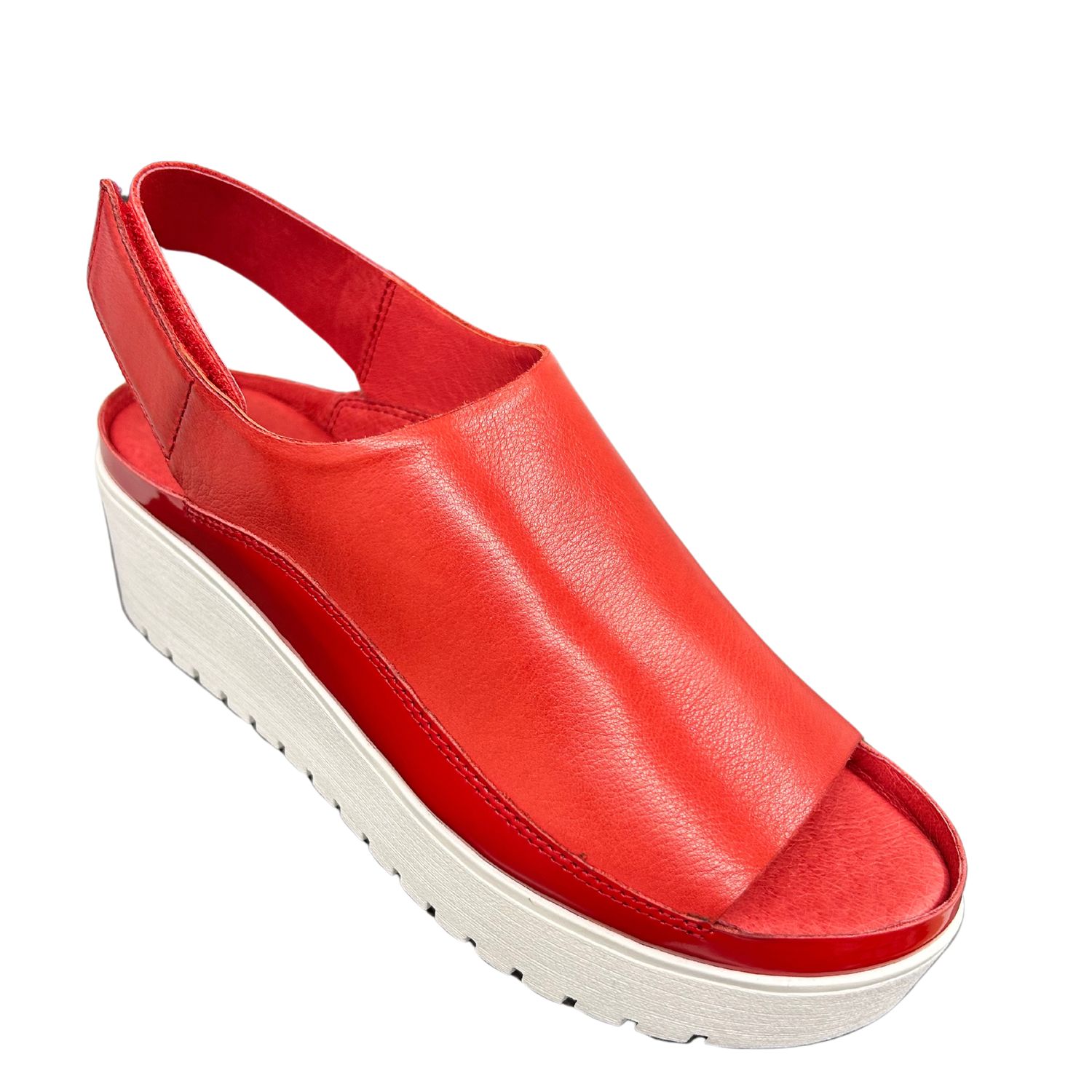Front angle view of a full coverage red leather sandal with a white sole.