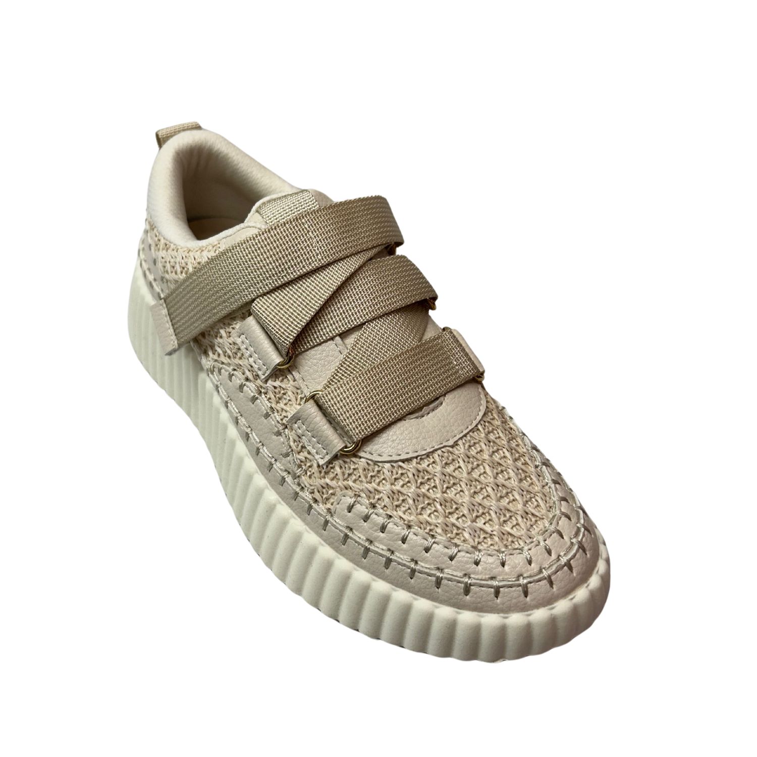Angled front view of a creamy fabric sneaker.  Pattern on the sneaker is reminiscent of a crochet pattern.  No laces - one strap that runs across the top and adjusts to fit.