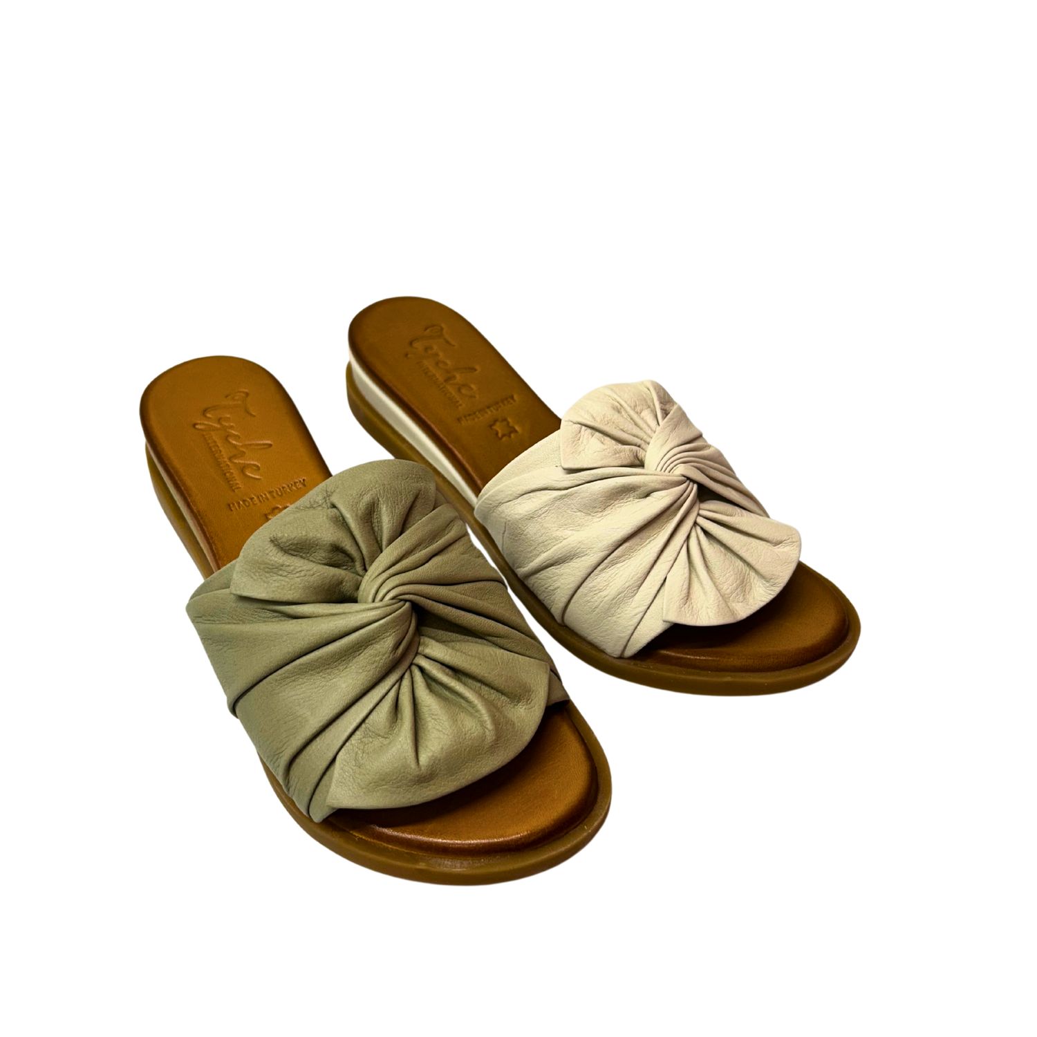 Angled front view of a slide sandal shown in 2 colors.  One is khaki and the other creamy leather.