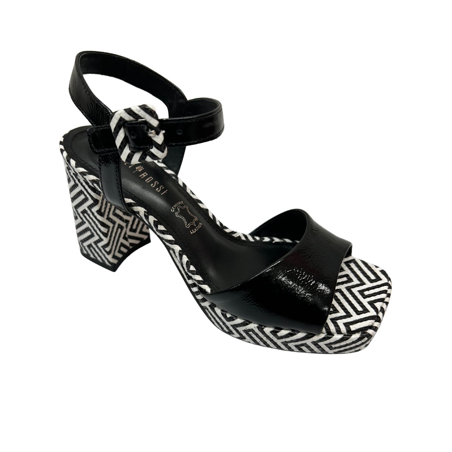 Angled front view of a platform sandal.  Upper is a black patent and the sole and heel are in a white/black chevron.